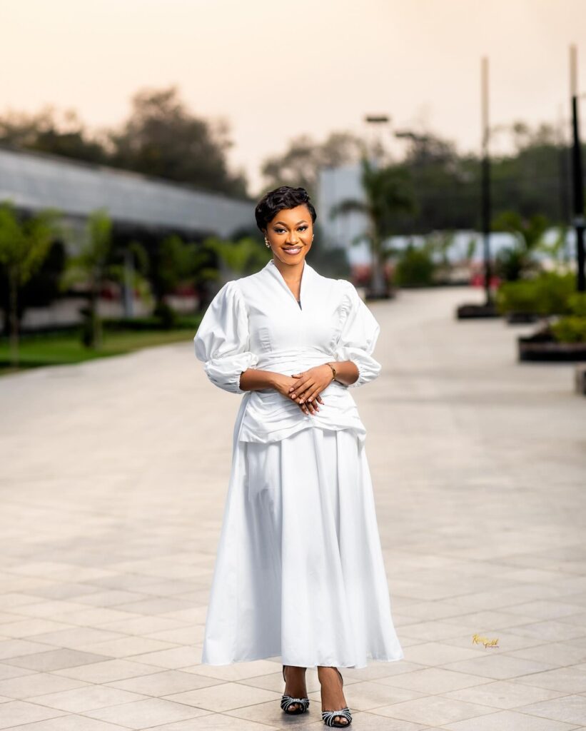 Picture of Efe Grace in a white straight dress. Her song in the name of Jesus is being featured as one of the top trending Ghana gospel songs.