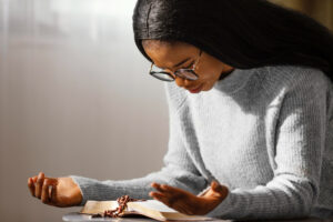 Picture of a young black woman praying in her quiet space to build her spiritual life.