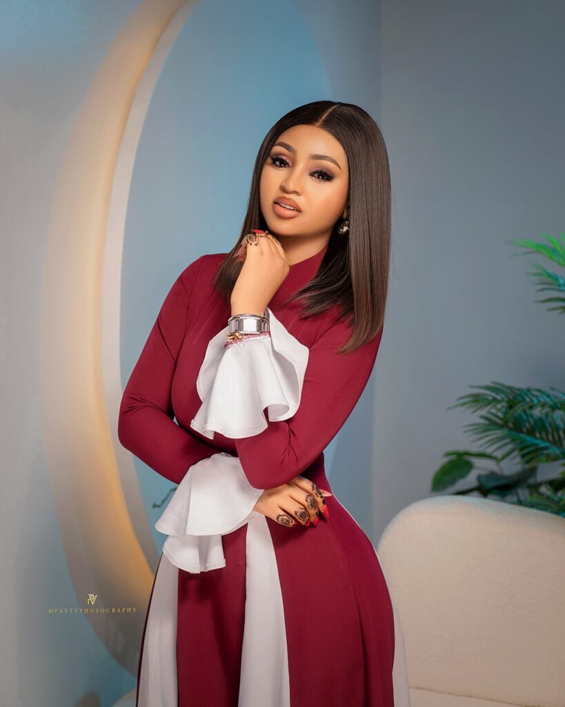 Picture of Regina Daniels in a straight wine dress with a touch of white design.