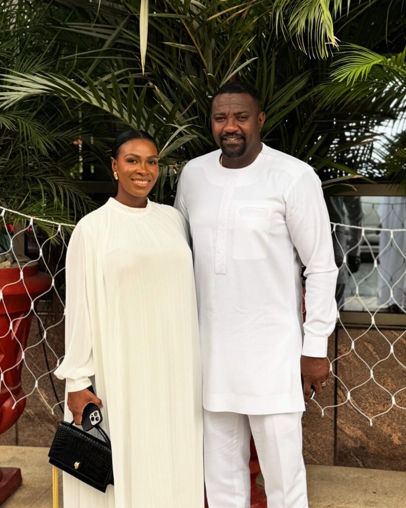 A picture of Ghanaian celebrity John Dumelo and wife dressed in white standing together, reflecting love under public attention.