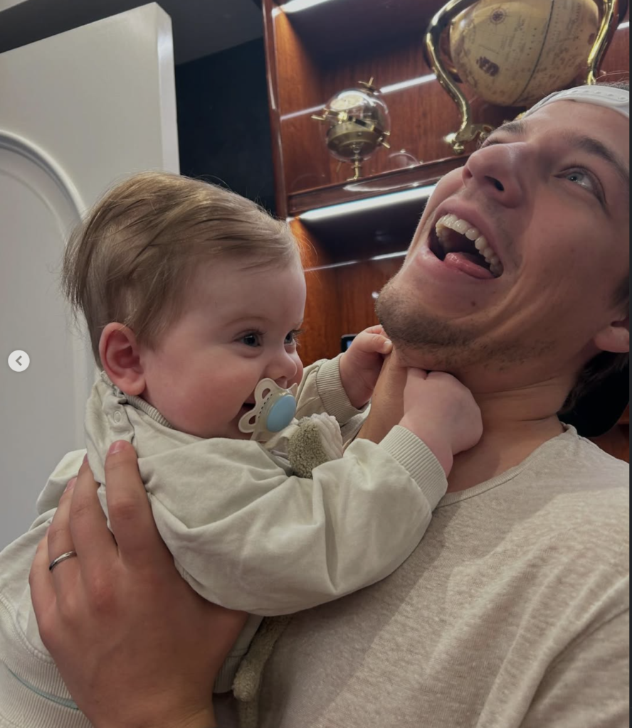 Millie Bobby Brown husband holding their adopted baby indoors, joyful expression, intimate parenthood moment