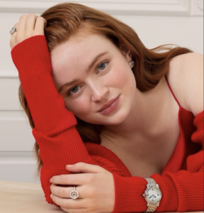 Close-up portrait of Sadie Sink in red outfit, relaxed pose with soft natural smile