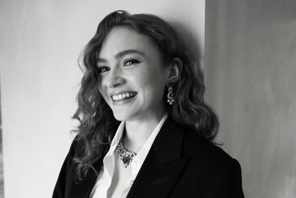 Black and white portrait of a smiling young actress in formal outfit, joyful expression