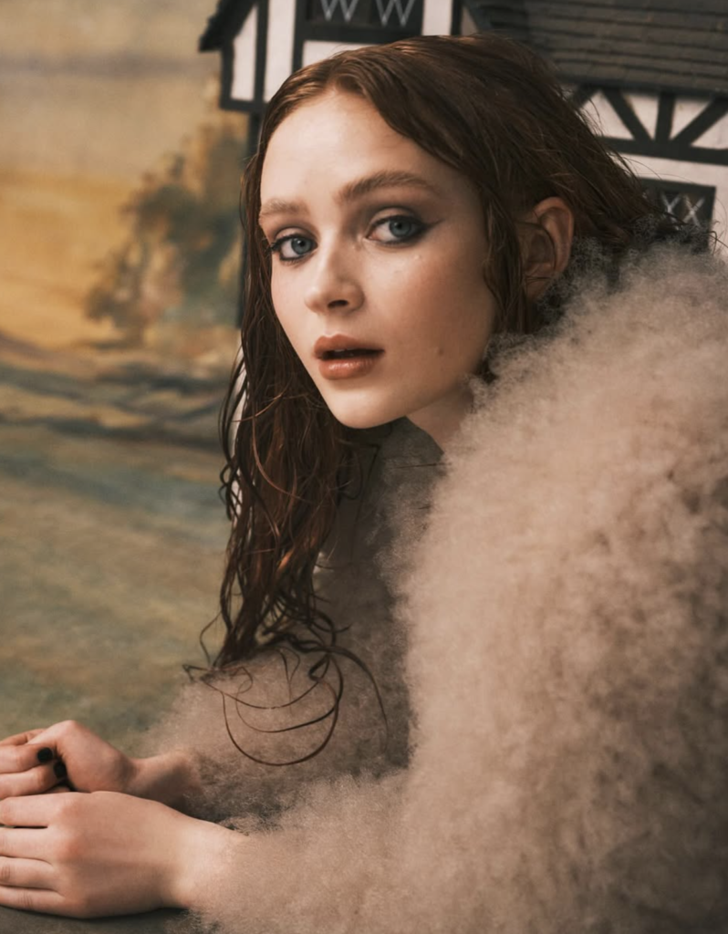 Young red-haired actress in dramatic setting with soft lighting and contemplative expression