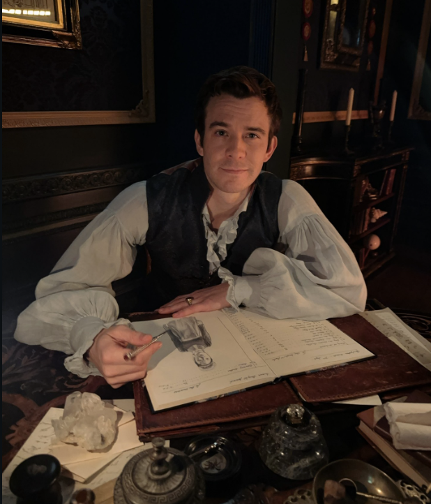 Benedict Bridgerton sitting at his desk sketching in Bridgerton Season 4 Part 2, thoughtful and conflicted expression