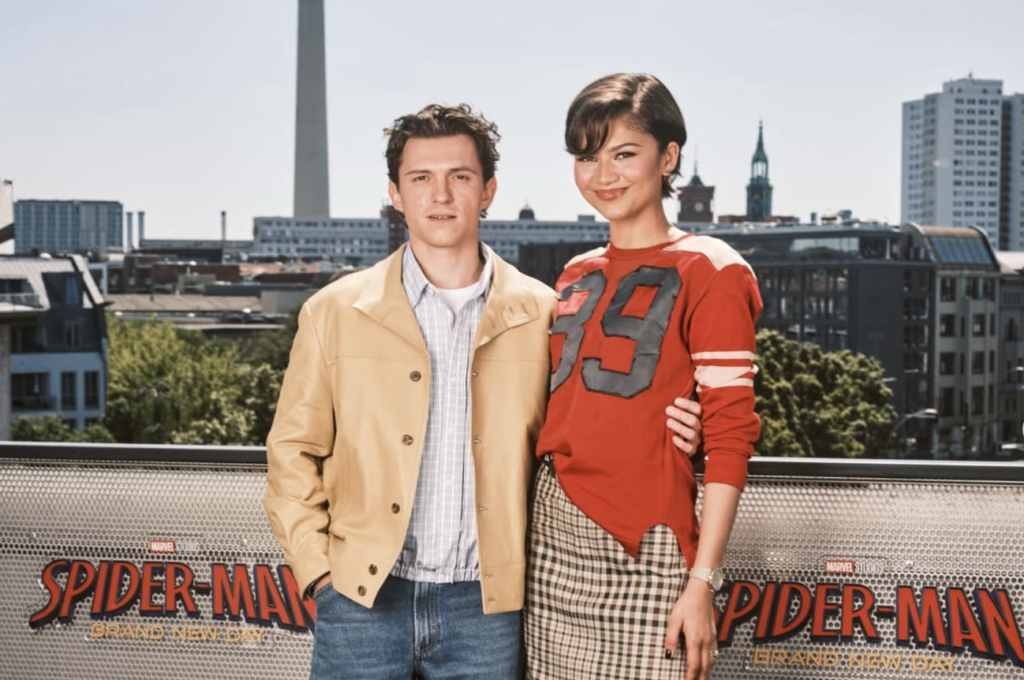 Tom Holland and Zendaya pose together during the Spider-Man: Brand New Day press tour, smiling for photographers.