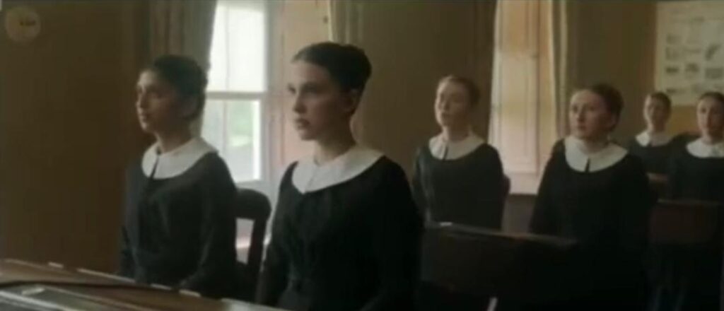 Young girls attend a lesson at Miss Harrison's Finishing School in Enola Holmes.