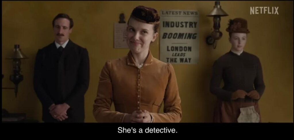 Enola Holmes smiles confidently while being introduced as a detective.