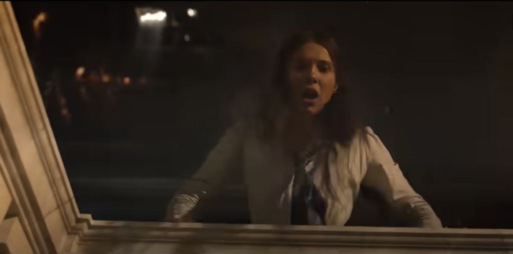 Enola Holmes climbs through a window during a suspenseful scene in Enola Holmes 3.