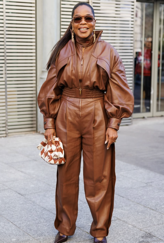 Oprah Winfrey wearing a brown leather outfit and sunglasses while walking outdoors