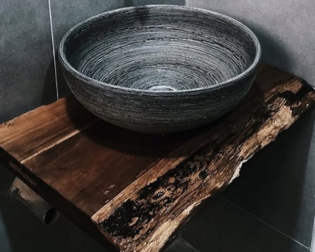 Natural wood slab used as a decorative shelf with a textured bowl in a modern interior