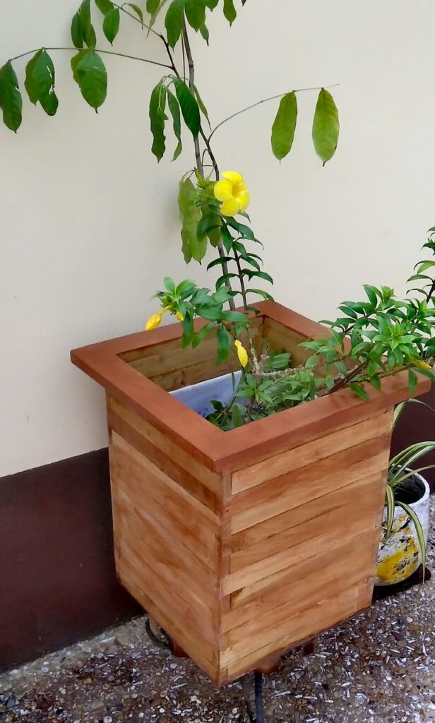 Large custom wooden planter containing flowering greenery in an outdoor space